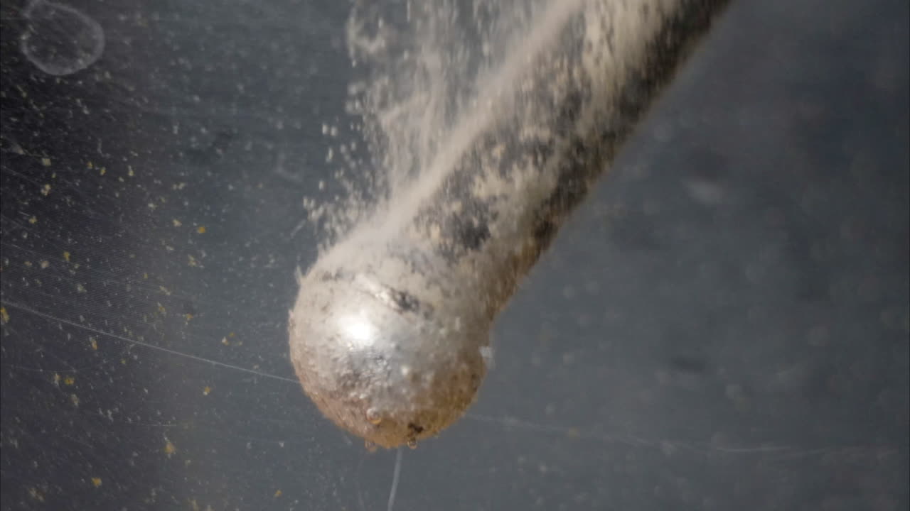 Macro close-up of tommy bar on c-clamp undergoing electrolysis. Timelapse