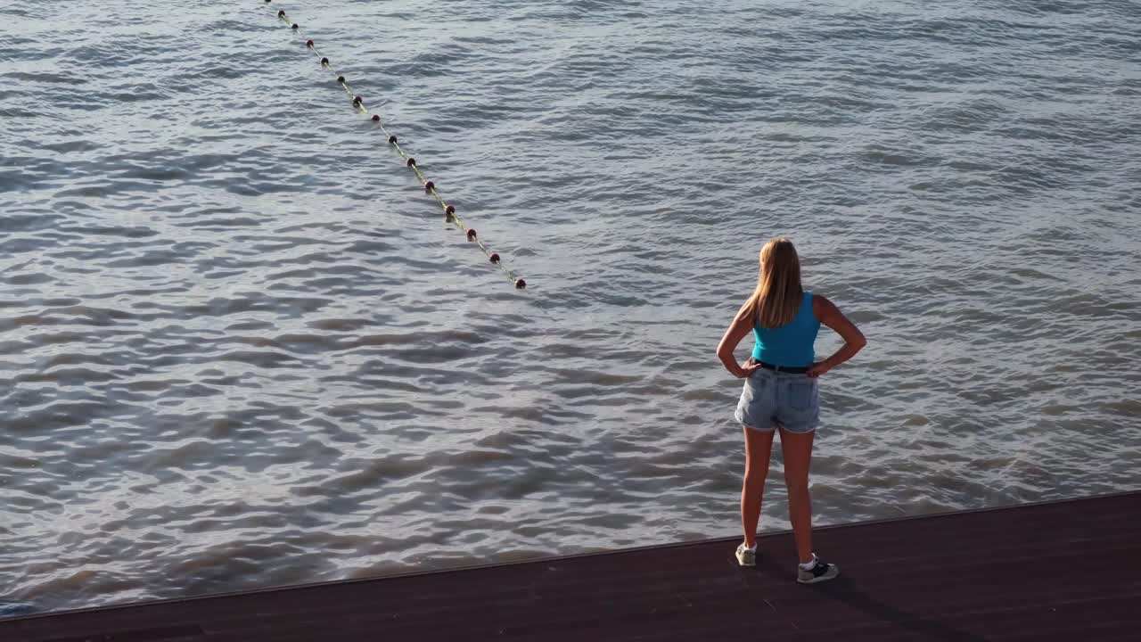 Woman standing on a pier looking out at the water