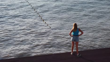 woman standing on a pier looking out at the water