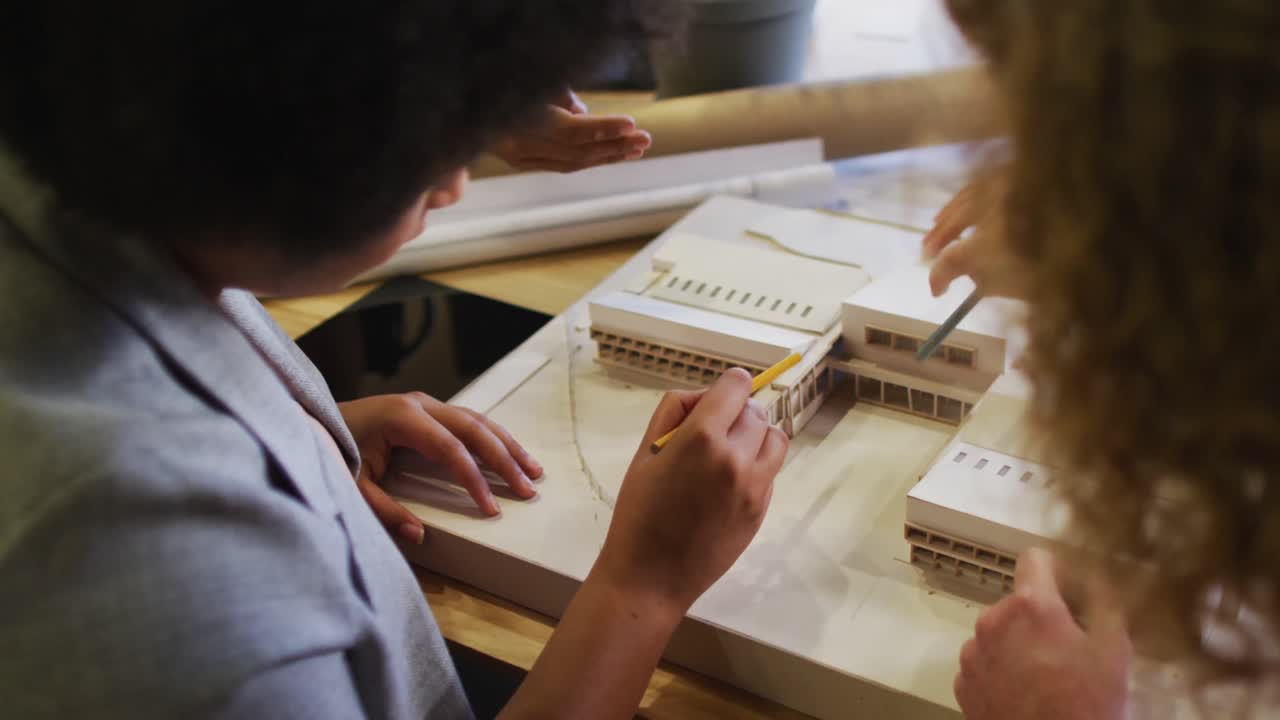 다양한 사업가 들 이 테이블 에 앉아서 사무실 에서 모델 과 함께 일 을 논의 하고 있다