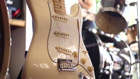 a vintage white electric guitar music instrument next to a drum set in a rock and roll garage band stage