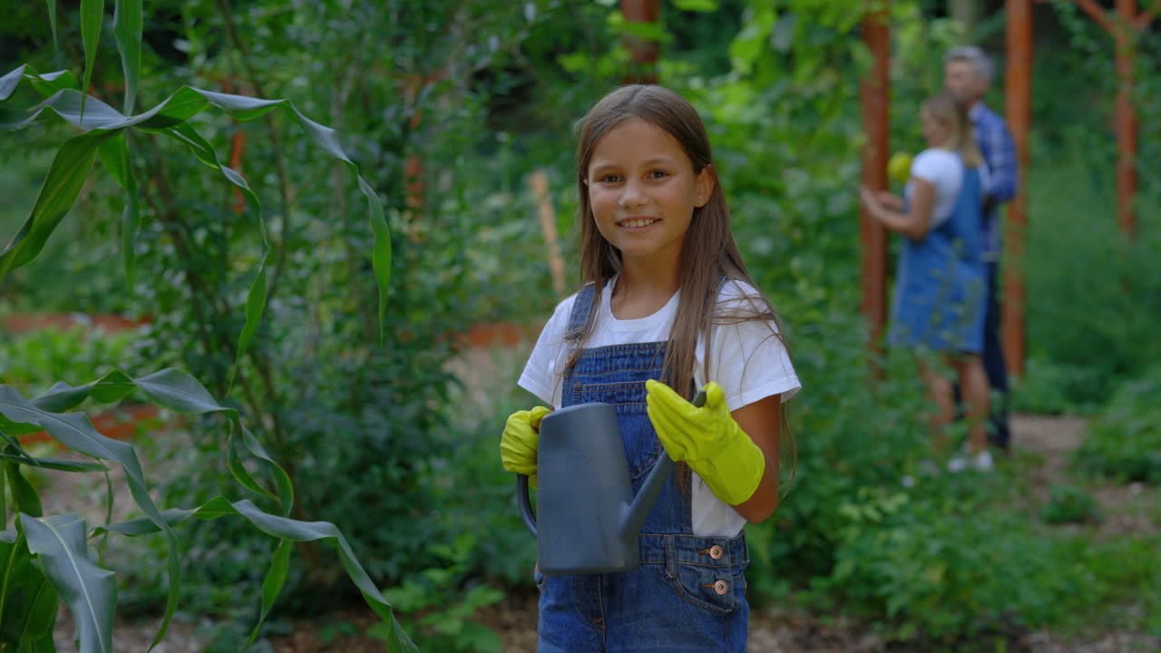 Girl Watering Plants in a Garden with Family