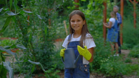 girl watering plants in a garden with family