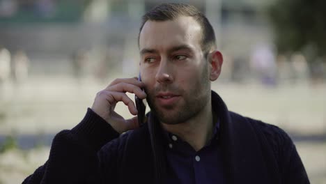 Cheerful-man-with-bristle-talking-on-smartphone-outdoor