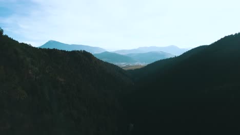 Drone-shot-over-pine-tree-mountain-valley-with-blue-sky