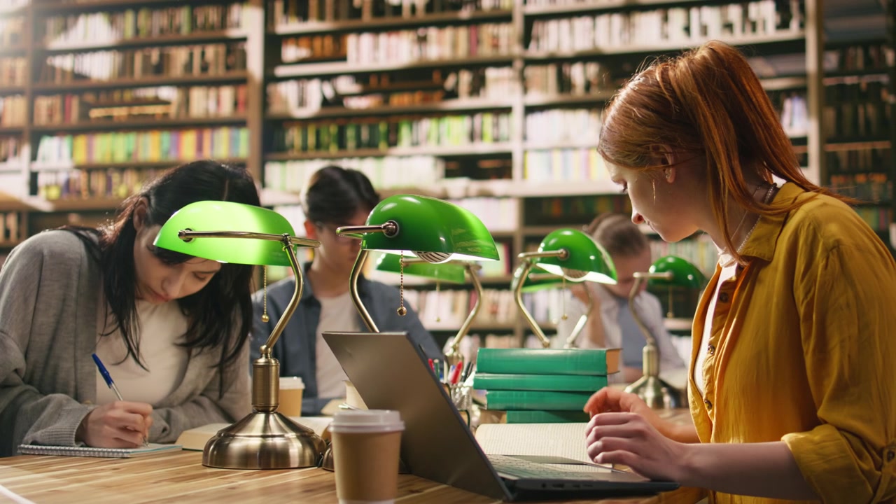 Giovane studente che legge un libro aperto e digita al portatile