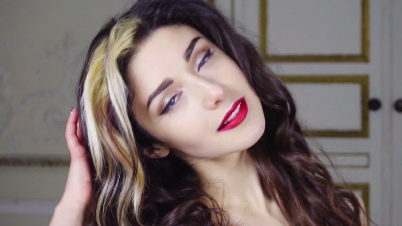 Young brunette woman with red lip looks at camera
