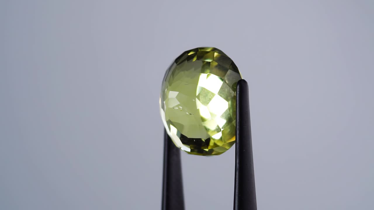 자연 황색 시트린은 회전 테이블에 있는 핀세저에 있습니다.