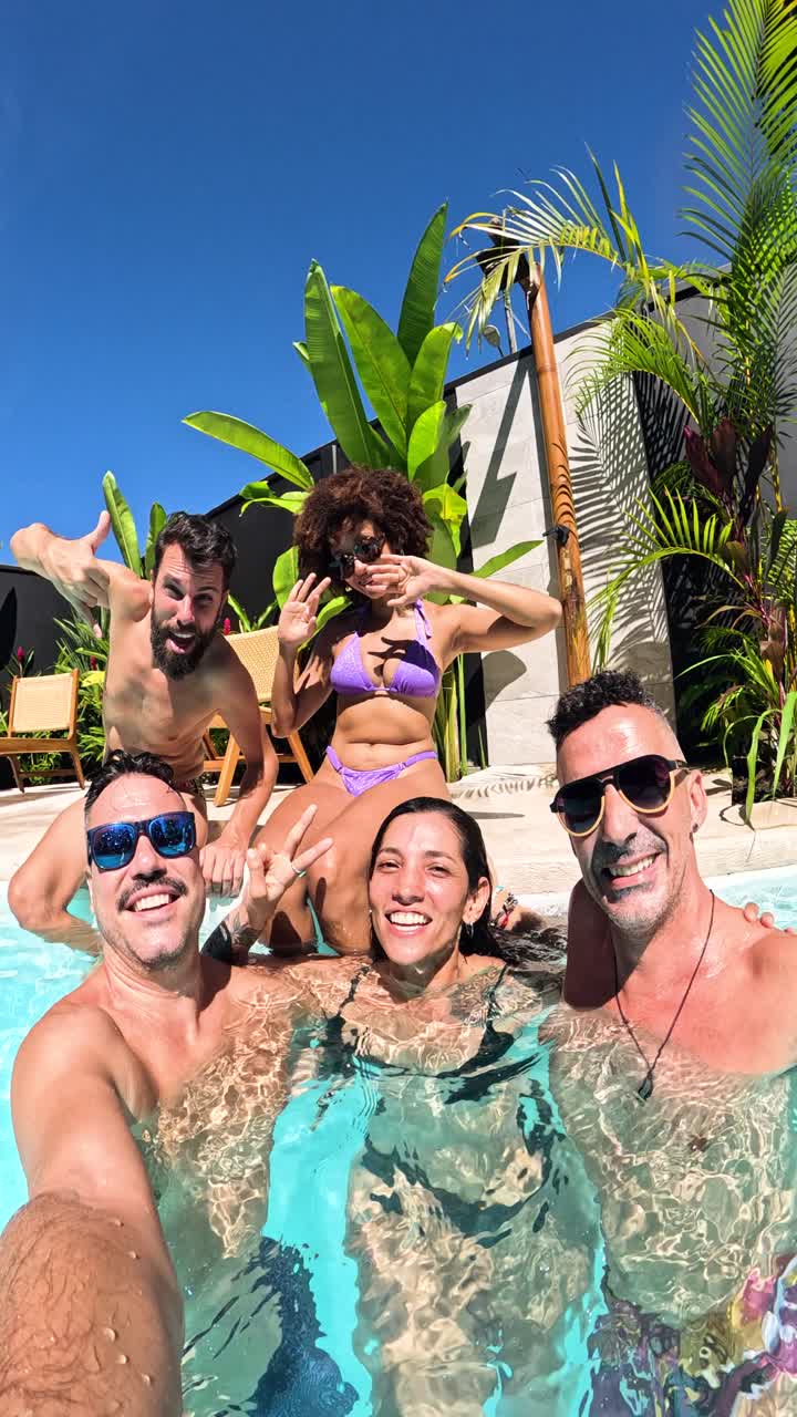 Amici felici che si scattano un selfie in una piscina tropicale.
