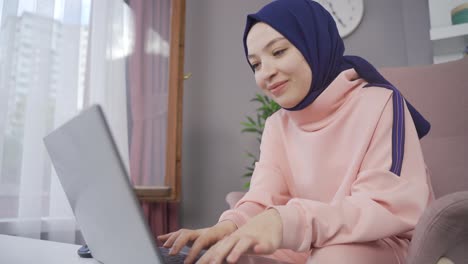 the hijab girl looking at the laptop is happy and successful.