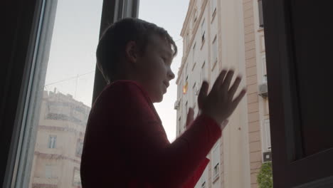 child in coronavirus lockdown applauding to health workers from open window