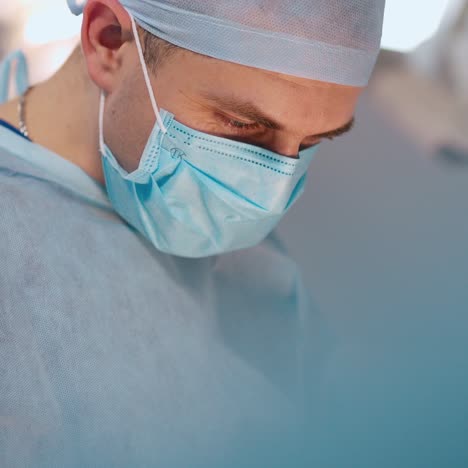 male doctor in mask. portrait of a surgeon in medical uniform looking down during surgical procedure in clinic. view from below.