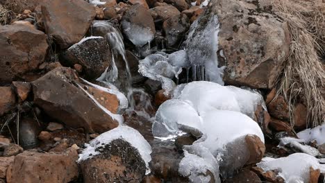 a small stream falling over snow covered rock