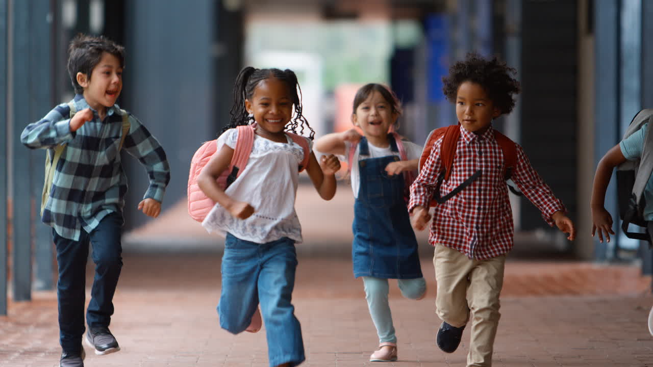 Group Of Multi-Cultural Elementary School Pupils Running Along Walkway Outdoors At School