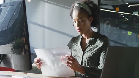 Happy-african-american-businesswoman-sitting-at-table-and-using-computer-at-office