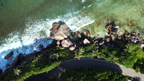 drone shot of road and rock boulders near the ocean, mahe seychelles