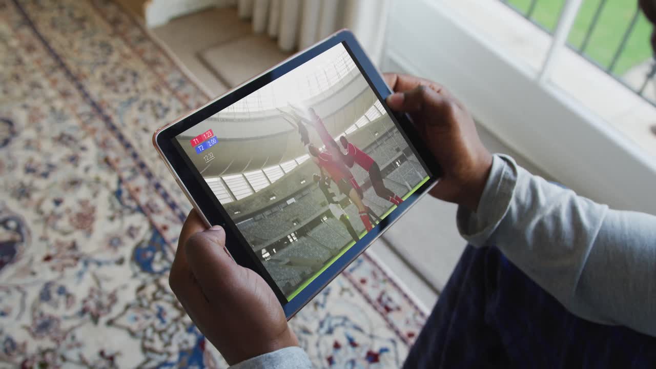 compuesto de un hombre sentado en casa, viendo un partido de rugby en la tableta