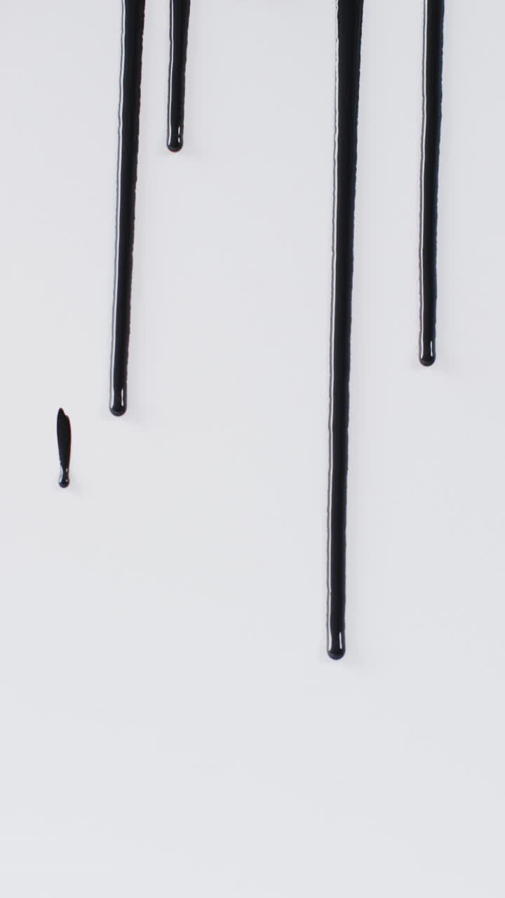 Vertical video of black paint stripes on white background with copy space, slow motion