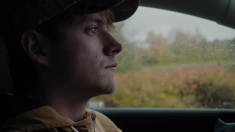 Young-White-Man-Parking-His-Car-In-The-Rain-While-Talking-and-Chewing-Gum---Handheld-Close-Up