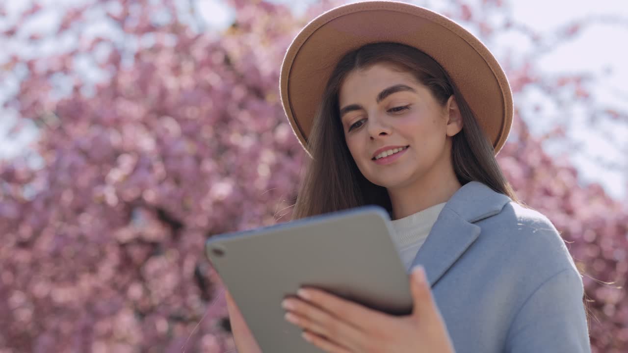 Woman using tablet in a cherry blossom tree