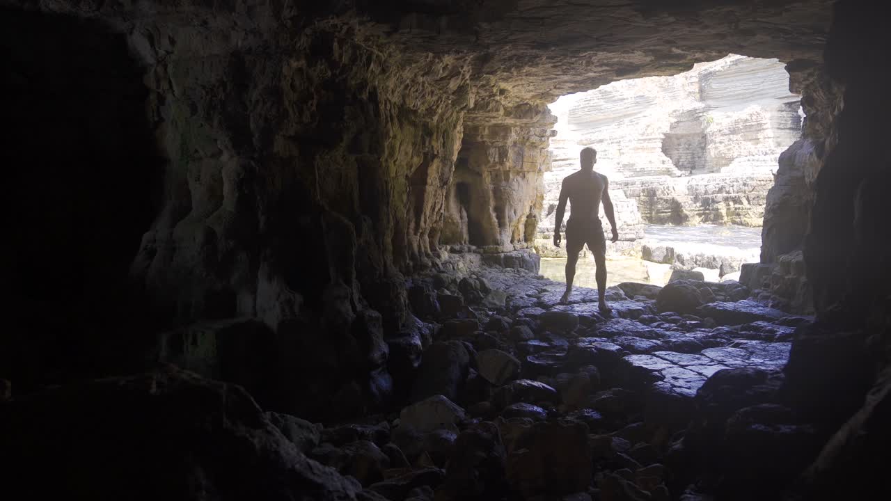 hombre joven caminando en la cueva del mar.