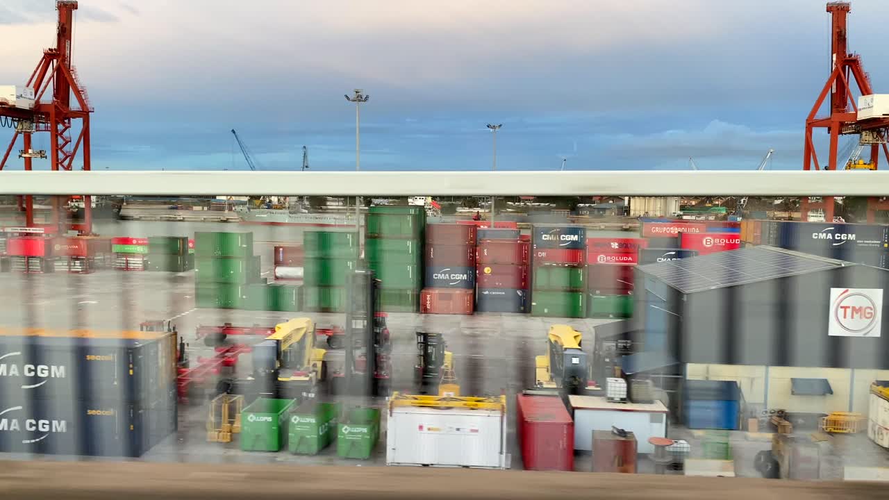 Driving past the industrial area of port of Seville city in south of Spain, many colourful shipping containers and working equipment in Sevilla, 4K shot