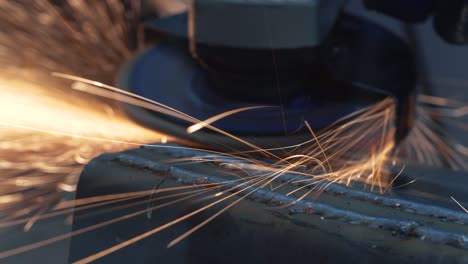el técnico utiliza un molinillo giratorio eléctrico para cortar y moler material metálico de la estructura. la reparación mecánica fabrica industrialmente herramientas de torneado manuales. las chispas brillantes de la luz disparan de cerca 4k