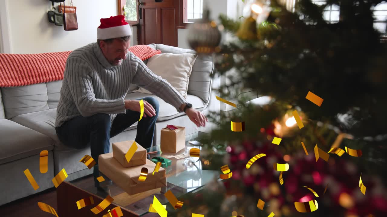 Mature man sitting on sofa confetti falling checking ribbon and moving gifts near tree for holiday