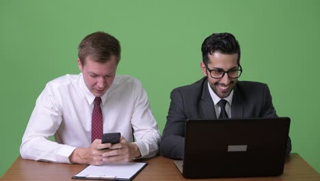 dos jóvenes empresarios multiétnicos trabajando juntos contra un fondo verde