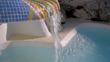 Wasser-Fließt-Aus-Einem-Mit-Mosaikfliesen-Gefliesten-Brunnen-In-Einen-Pool