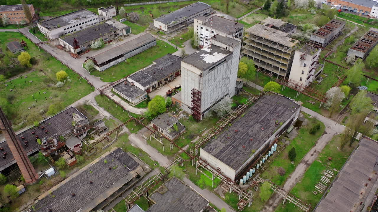 Large territory of abandoned plant. Damaged buildings of an old factory. Ruined industry in springtime. Aerial view.