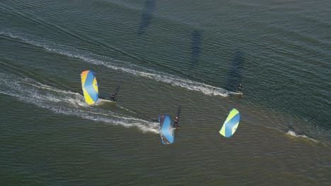 kiteboarders being pulled fast across the sea water by power kites