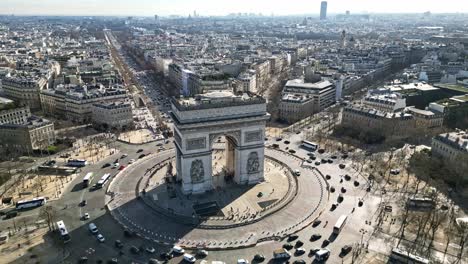 triumphal arch or arc de triomphe and car traffic on roundabout with paris cityscape, france