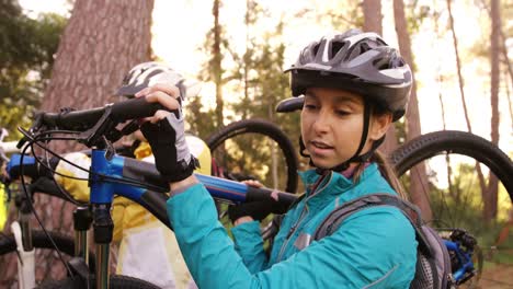 mountain biking couple carrying bicycle in the forest