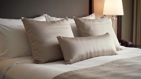 cozy and inviting hotel bedroom with plush beige pillows and elegant lighting, creating a comfortable atmosphere for relaxation and sleep
