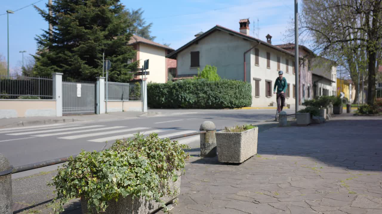 hombre montando un scooter eléctrico rápido en una pasarela en una tranquila ciudad europea, estática