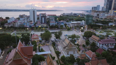 aerial video of temple rooftops in phnom penh at dusk, with intricate spires and glowing lights lining the grounds
