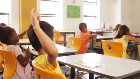 School-kids-raising-hand-in-classroom