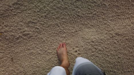 Bare-feet-of-man-in-swimming-trunks-walking-on-a-beach