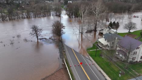 Vista-Aérea-De-Una-Calle-Inundada-Con-árboles-Sumergidos-Y-Casas-Cerca-De-Una-Carretera-Despejada