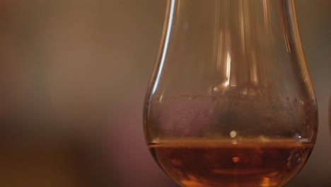 Slow horizontal pan of whisky glasses with amber liquid, warm lighting, and blurred background