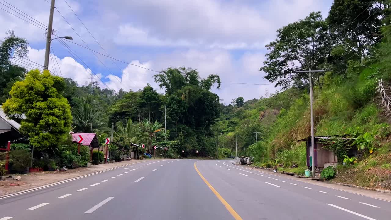 Empty highway curves through tropical mountain landscape with vibrant greenery. Ideal for travel, driving, or cinematic transitions