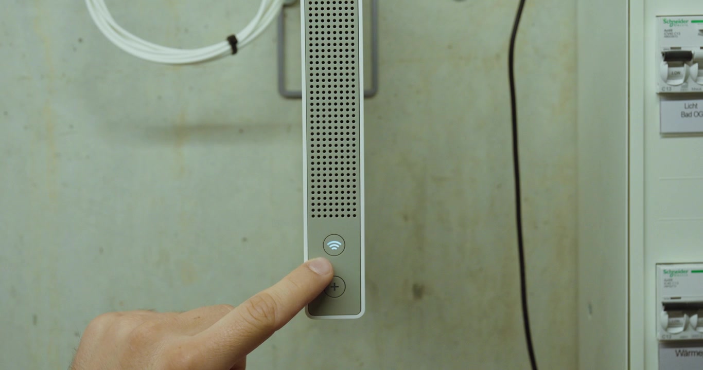 Close-up of a hand pressing the WLAN activation button on a network router installed in a technical control room. Concept of wireless internet, network connectivity, broadband access