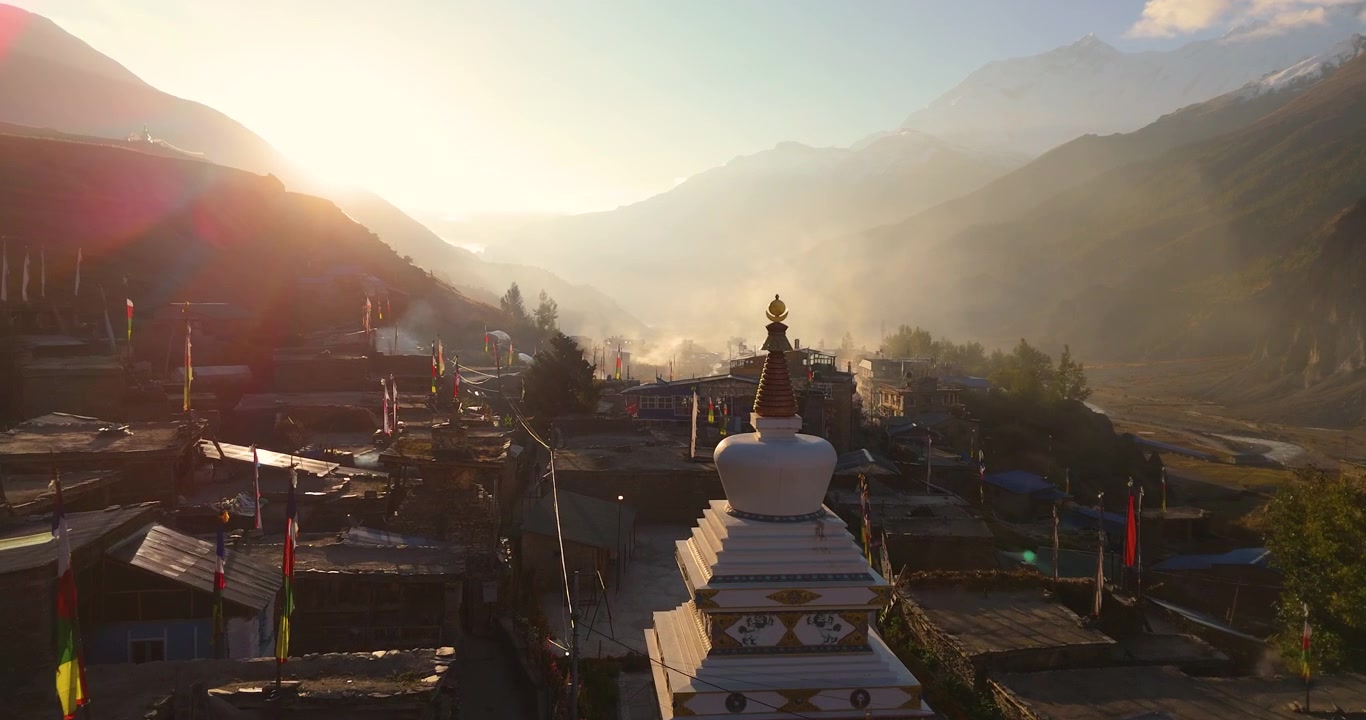 Droneoptagelse af solopgang over en traditionel Himalaya-landsby indhyllet i tåge og dis langs den barske Annapurna Circuit, Manang Nepal.