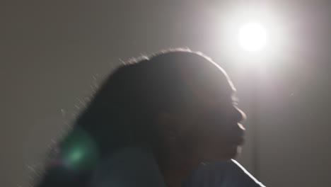 backlit head and shoulders studio portrait shot of young woman dancing in spotlight 2