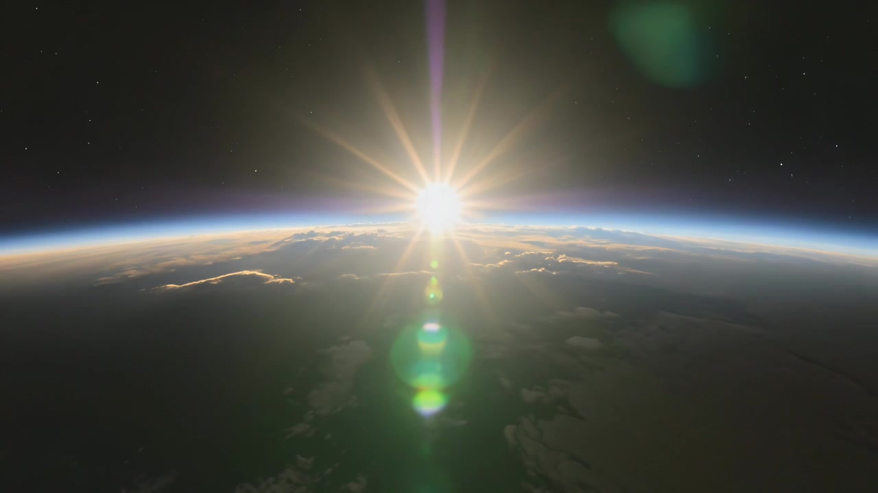 Bright point appearing sun ascending over Earth limb from LEO making lens flare and lighting clouds