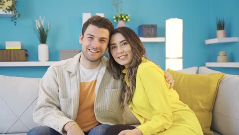 Cheerful-and-happy-young-couple-smiling-positively-looking-at-camera-in-their-home.