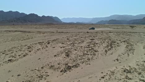 aerial view of a fast sports car driving down a remote desert road