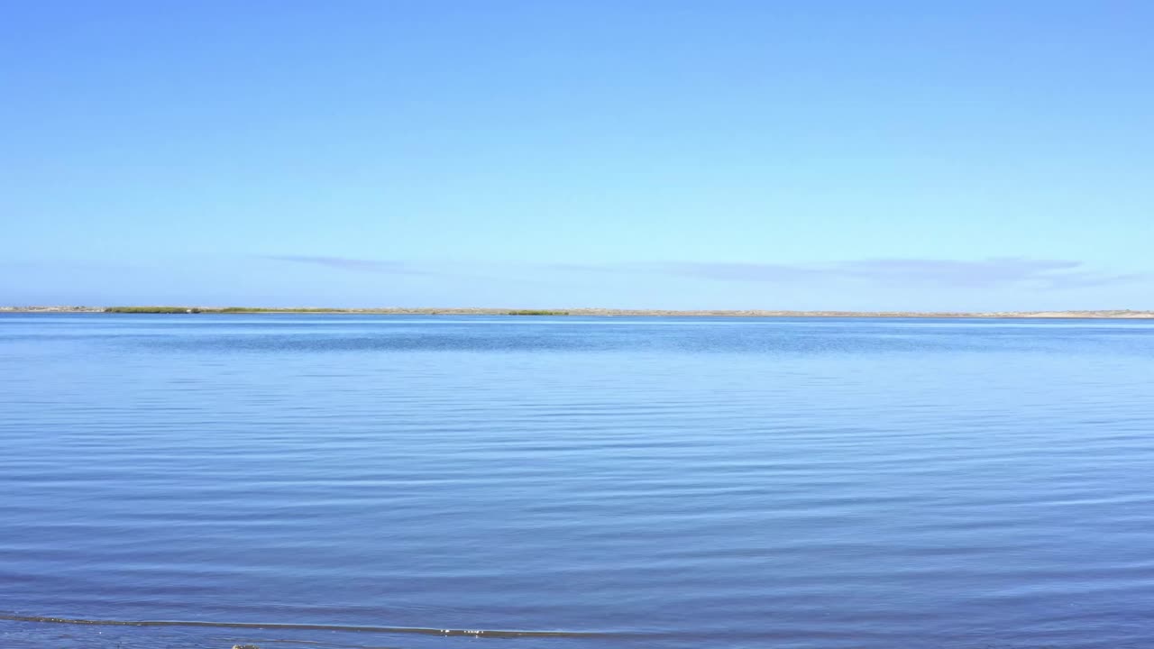Peaceful aerial view glides over the calm, reflective water surface at Cabo San Lucas, Mexico