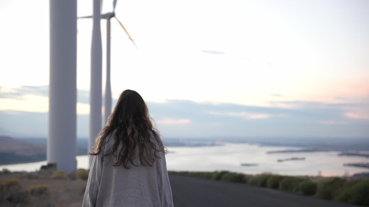 느린 동작으로 일몰에 풍차 아래를 걷는 모델